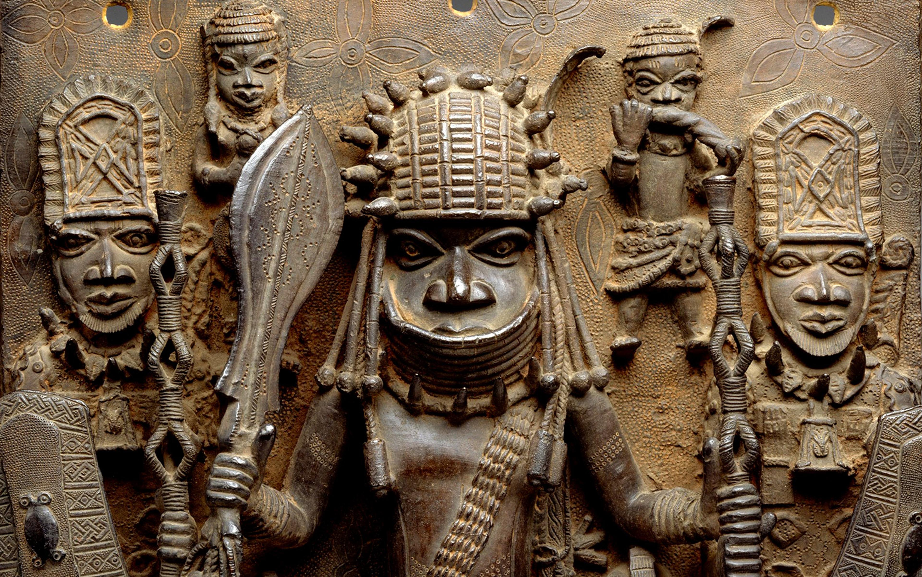 Bronze relief sculpture of five figures adorned in detailed attire, holding weapons on an intricately patterned background.