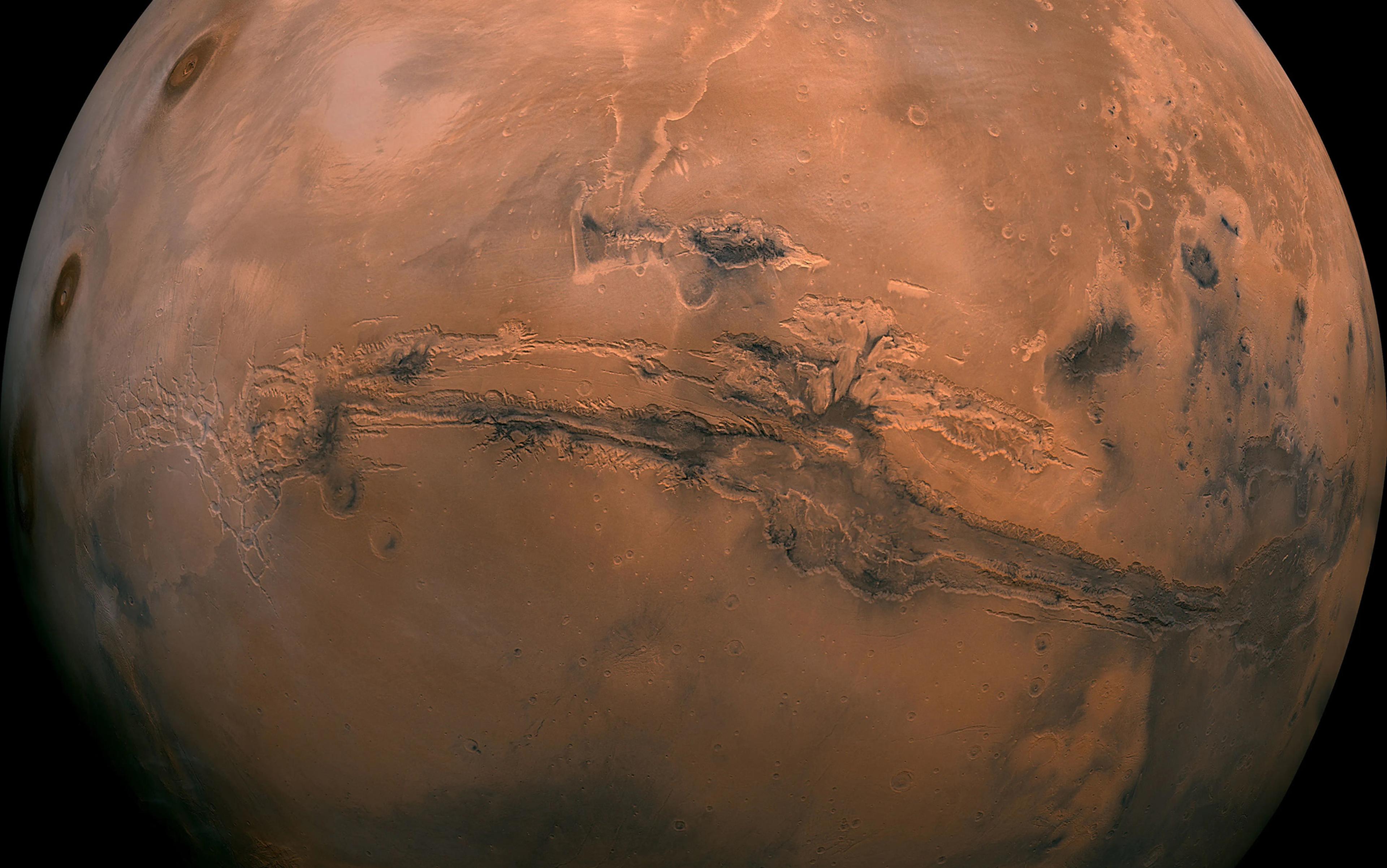 A detailed NASA photo of Mars showing the Valles Marineris canyon system with cratered terrain and dust-streaked surface.
