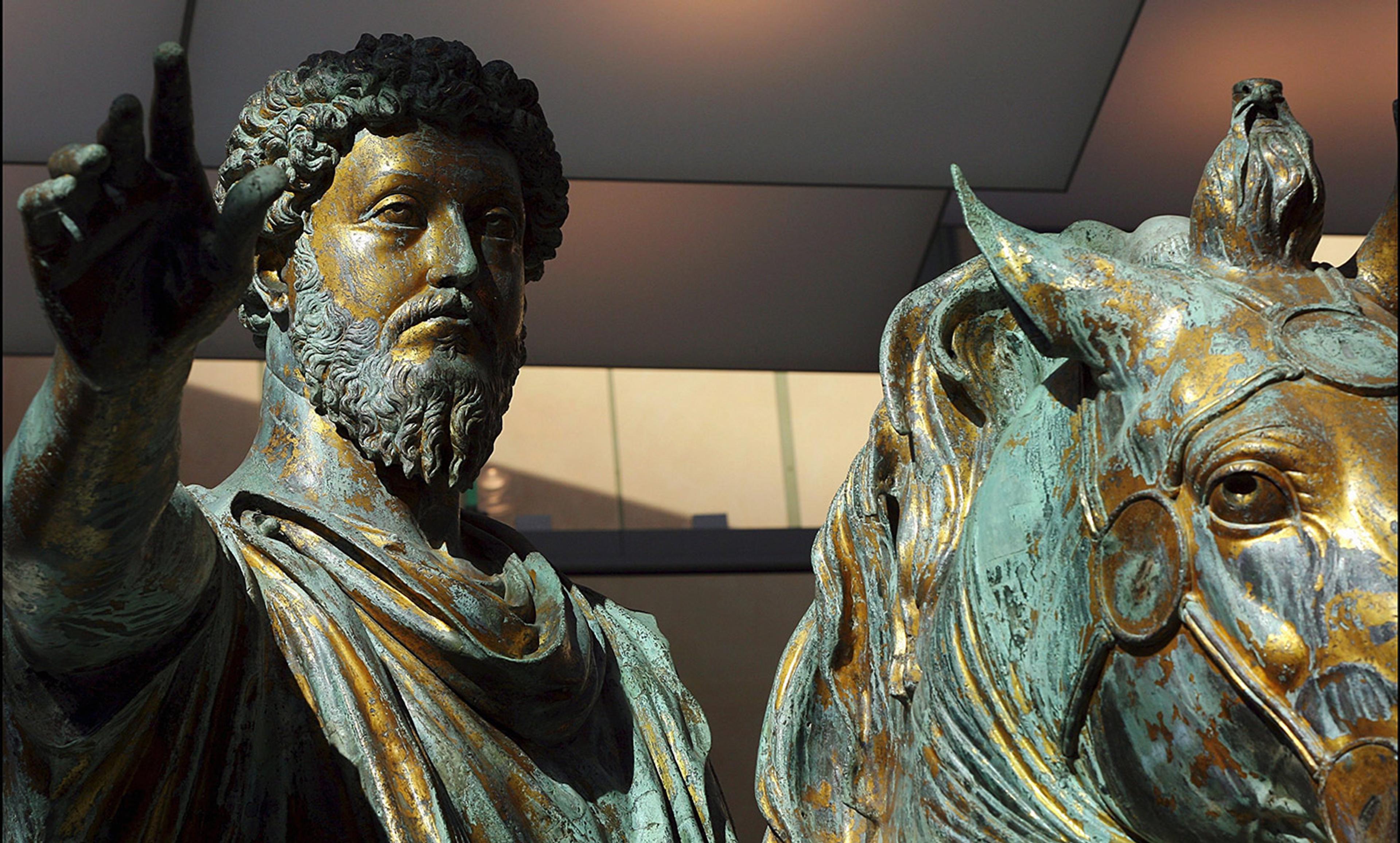 Bronze statue of a bearded man raising his arm next to a horse’s head.